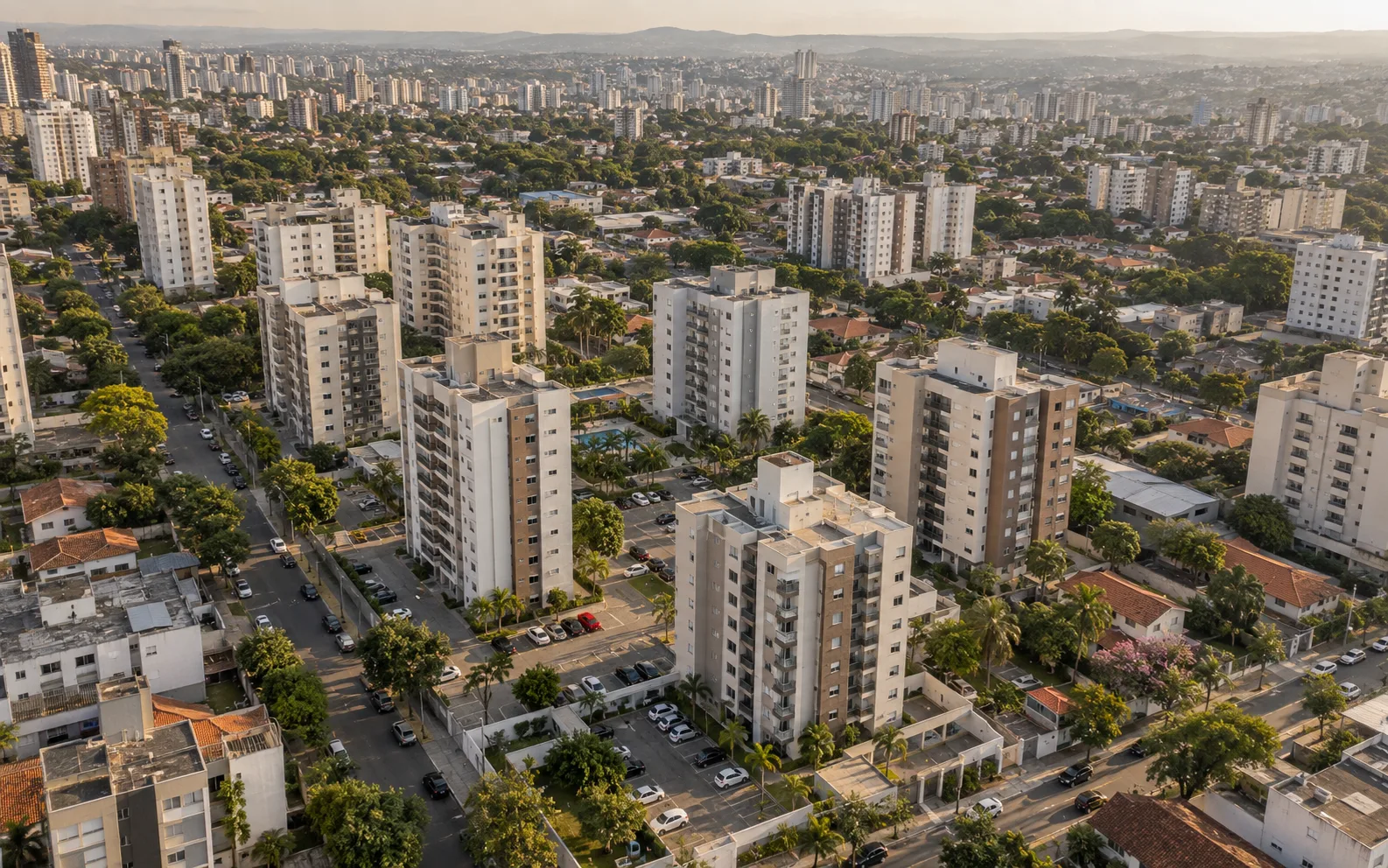 Vista aérea de cidade com condomínios de classe média, prédios residenciais e ruas arborizadas.